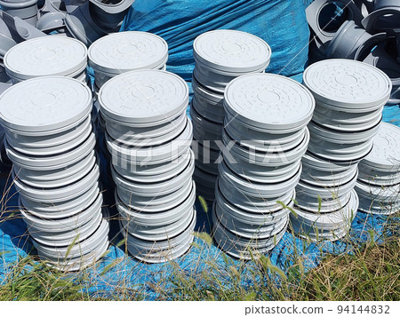 Manholes and adjusters piled up at a construction site 94144832