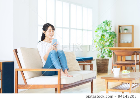 Women's living room smartphone lifestyle casual Women's living room smartphone lifestyle casual 94145203