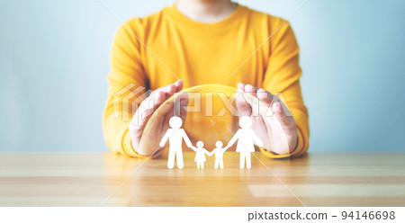 Hand protecting family on wood table. Healthcare and life insurance concept 94146698