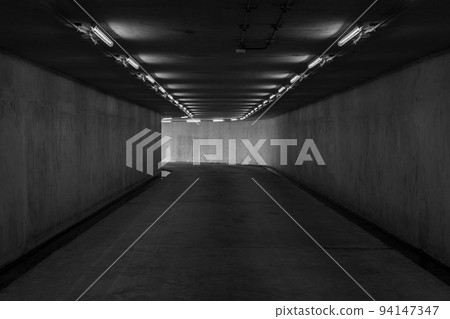 Road tunnel black and white, night illuminated, Urban tunnel without traffic, illuminated city highway tunnel with spotlights black and white. Road tunnel black and white, night illuminated, Urban tunnel without traffic, illuminated city highway tunnel with spotlights black and white. 94147347