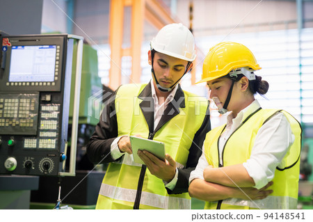 Factory workers check microchip stock in tablet by machinery Factory workers check microchip stock in tablet by machinery 94148541