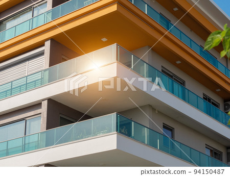 New apartment building with large balconies with glass railings. 94150487