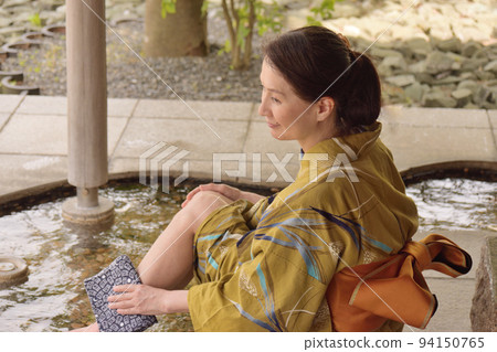 Senior woman wearing a yukata and enjoying a footbath at a tourist spot 94150765