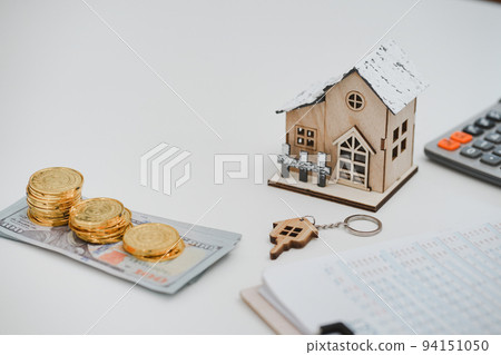 Stacking of US Dollar bank notes , model house, contract agreement on desk. Real estate, home loan and investments concept. 94151050