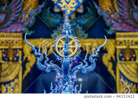 Gold rowel, the symbol of buddhist religion on the Thai blue art style pole with temple background. 94151421