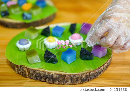 Thai Chef's hand is decorating Varieties traditional colorful Thai desserts set; steaming flour, black custard, coconut custard & steaming bean, layer pudding cake Thai Chef's hand is decorating Varieties traditional colorful Thai desserts set; steaming flour, black custard, coconut custard & steaming bean, layer pudding cake 94151888