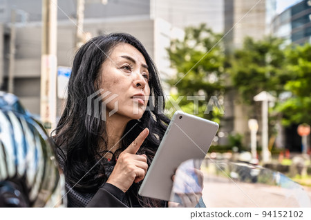 A female rider moving around Yokohama on a large cruiser bike Confirming the route on a tablet A female rider moving around Yokohama on a large cruiser bike Confirming the route on a tablet 94152102