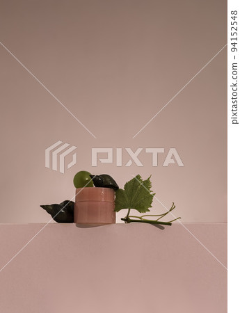 Snail on jar with face cream with snail mucus and grape green leaves. Use of snail mucus in cosmetology. Skin care and beauty concept 94152548