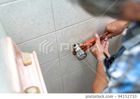 Asian man tries to fix and repair pipe / shower in the old restroom. 94152710
