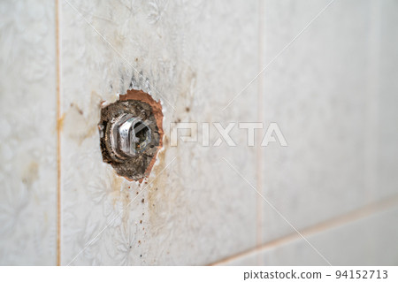 broken pipe at the tile wall in the restroom. 94152713