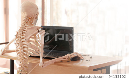 Skeleton in a medical mask using a computer in the office 94153102