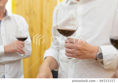 close up to the hands of Two white shirt businessman hold wine glass, talk and negotiate in business and political issue at the dinner party. 94153157