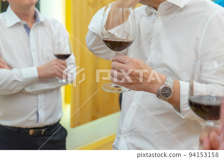 close up to the hands of Two white shirt businessman hold wine glass, talk and negotiate in business and political issue at the dinner party. 94153158