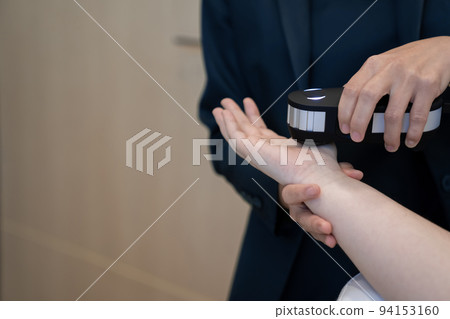 Woman doctor in a dark uniform suit is testing a patient's hand for her health statistic that show on the laptop monitor 94153160