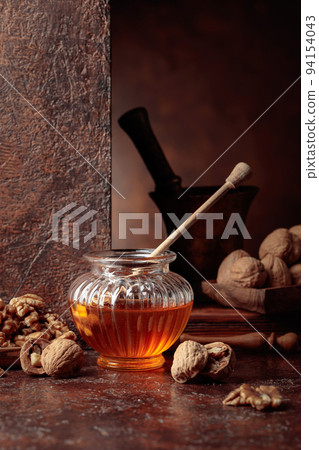 Honey and walnuts on a kitchen table. Honey and walnuts on a kitchen table. 94154043