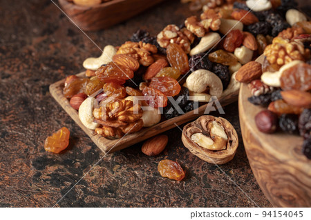 Mix of nuts and raisins on a brown rustic background. 94154045