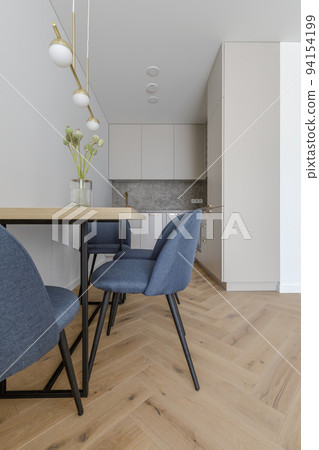 Modern minimalist kitchen and dining room interior design with wooden furniture, oak floor. blue chairs. Aesthetic simple interior design concept. Modern minimalist kitchen and dining room interior design with wooden furniture, oak floor. blue chairs. Aesthetic simple interior design concept. 94154199