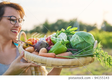 Close up basket of fresh raw organic vegetables in farmer hands 94155143