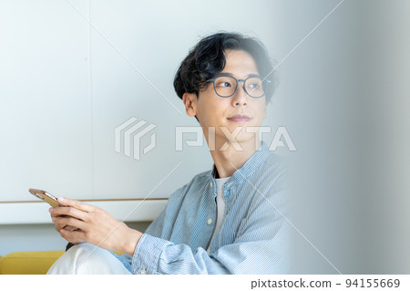 A young man operating a smartphone 94155669