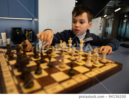 Concentrated Caucasian school boy developing chess strategy, playing board game 94156200