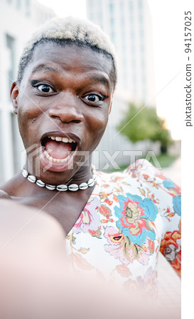 Cheerful black homosexual man in dress looking at camera with opened mouth 94157025