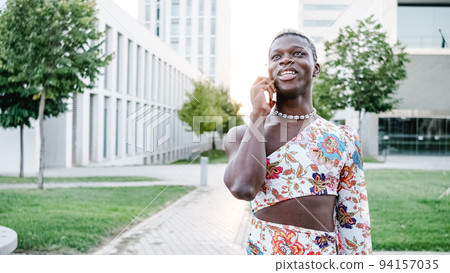 Young African transgender person speaking on the phone at the town 94157035