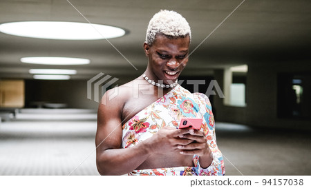 Androgynous black person using cellphone in modern interior Androgynous black person using cellphone in modern interior 94157038