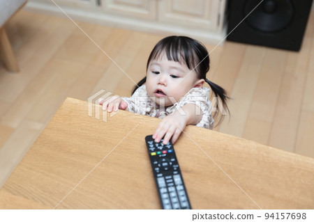 A 1-year-old girl pranking the TV remote control A 1-year-old girl pranking the TV remote control 94157698
