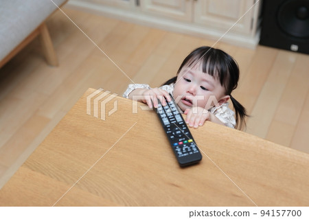 A 1-year-old girl pranking the TV remote control 94157700