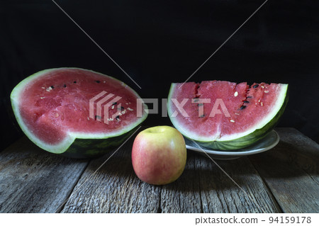 Ripe watermelon and apple on a wooden table Ripe watermelon and apple on a wooden table 94159178
