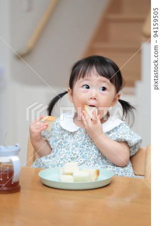 一個 1 歲的女孩抓著麵包吃 94159505