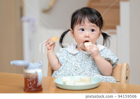 一個 1 歲的女孩抓著麵包吃 94159506