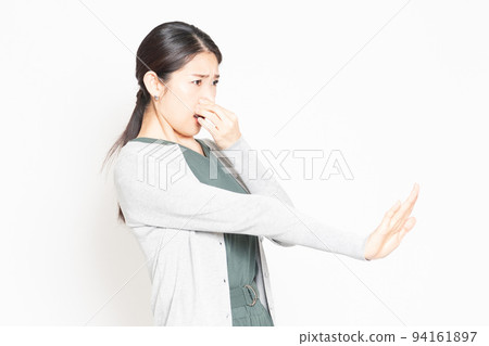 A woman who is suffering from stinks and is pinching her nose 94161897