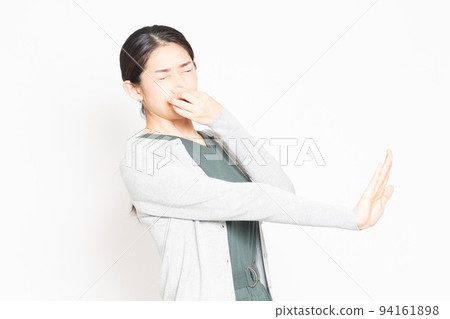 A woman who is suffering from stinks and is pinching her nose 94161898
