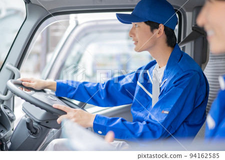 Young carrier male employee driving truck in uniform 94162585