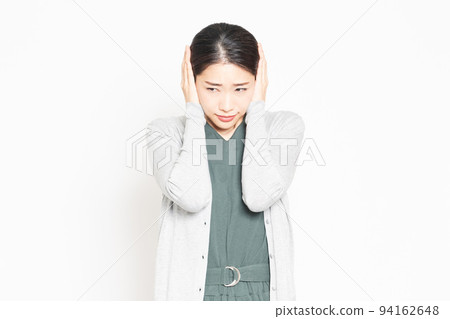 A woman covering her ears because of noise A woman covering her ears because of noise 94162648
