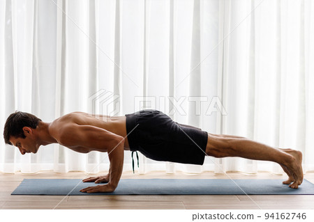 Middle-aged man doing chaturanga yoga pose during his morning physical routine 94162746