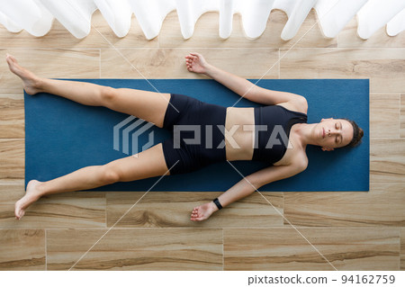 Young fitness woman enjoying shavasana yoga pose. Top view image 94162759