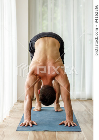 Middle-aged man doing downward facing dog yoga pose during his morning physical routine Middle-aged man doing downward facing dog yoga pose during his morning physical routine 94162866