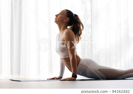 Young woman doing yoga vinyasa flow at home in the morning 94162882