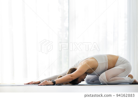 Young woman meditating in yoga child pose during her morning yoga routine 94162883