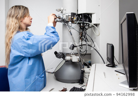 Young female scientist loading a specimen using a sample holder into a transmission electron microscope Young female scientist loading a specimen using a sample holder into a transmission electron microscope 94162998
