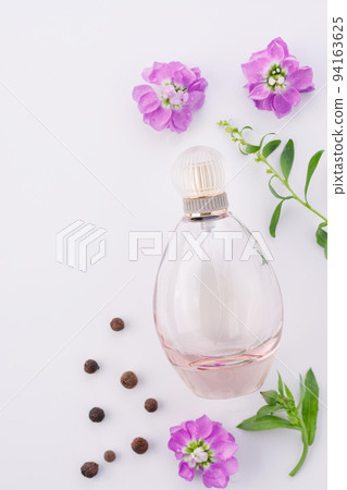 Flat lay composition. Elegant perfume on a white background with purple flowers and pepper. Ingredients and perfume. Flat lay composition. Elegant perfume on a white background with purple flowers and pepper. Ingredients and perfume. 94163625