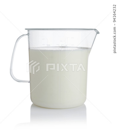 Milk in a plastic measuring cup isolated. Milk in a plastic measuring cup isolated. 94164232