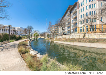 Small river in the middle of mid-rise resiedntial buildings at San Antonio, TX 94164264