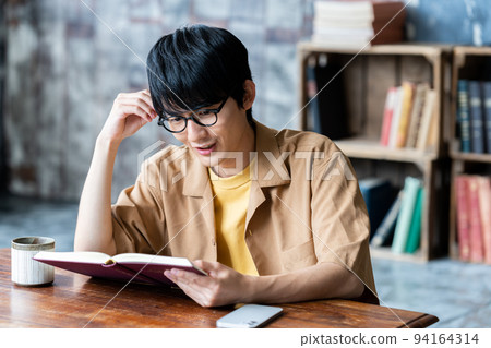 Young man with glasses reading in the room Young man with glasses reading in the room 94164314