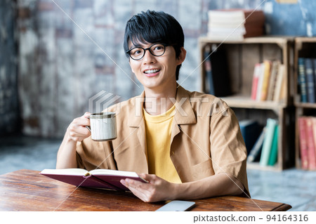 Young man with glasses reading in the room 94164316