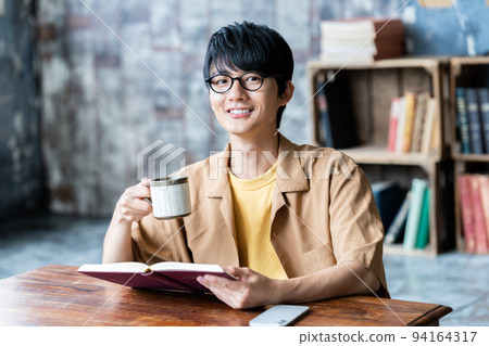 Young man with glasses reading in the room 94164317