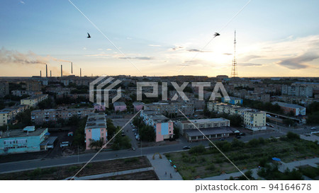 A flock of birds fly over the city at sunset. A flock of birds fly over the city at sunset. 94164678