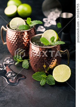 Moscow mule cocktail in a copper mug with lime and mint and wooden squeezer  94164755
